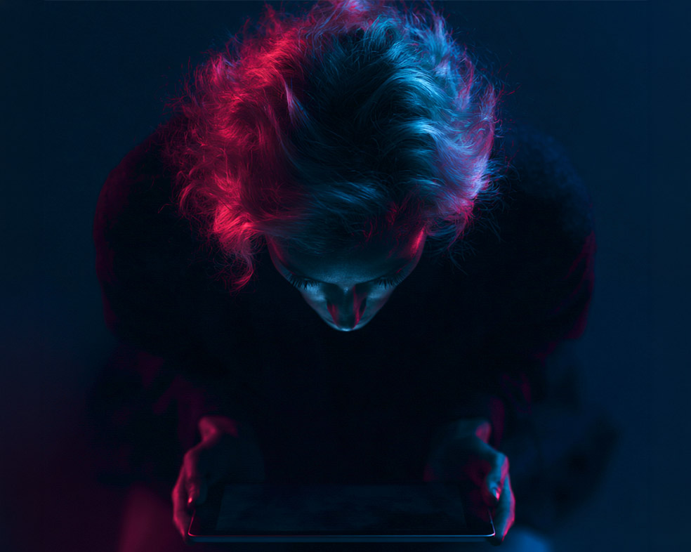 A designer at work on a tablet, lit in red and blue